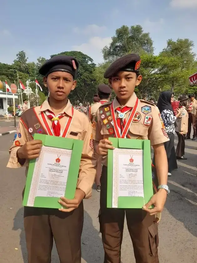 Dua murid SMPIT Safinatunnajah memegang piagam Tanda Pramuka Garuda